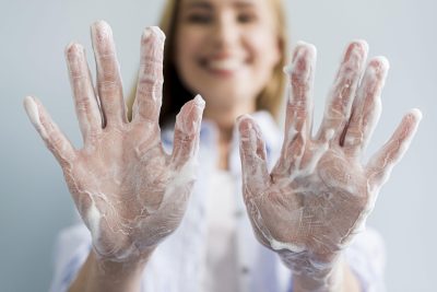 defocused-woman-showing-her-hands-covered-soap